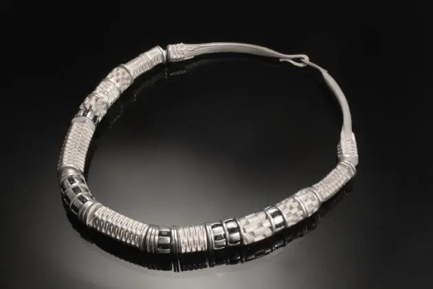 A Metallic Necklace With Rolled Cube With Details