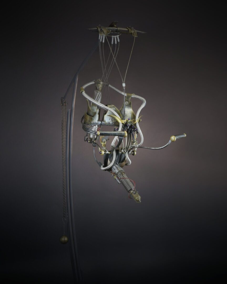 A sculpture of a mechanical device hanging from a pole.